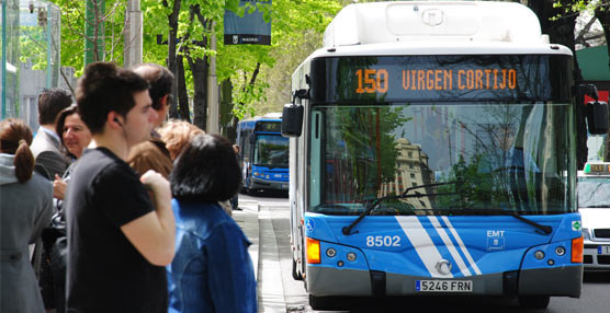Un grupo de pasajeros espera la llegada de varios autobuses de la EMT de Madrid.