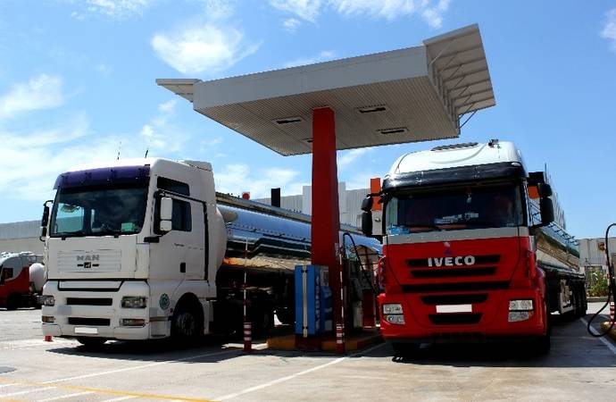 Dos camiones echan combustible en una estación de servicio.