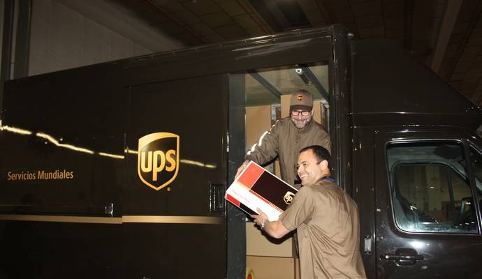 El embajador de EEUU en España, James Costos, recibe un paquete de las manos de Wilfredo Ramos, , director general de UPS España y Portugal.