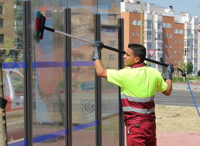 Un empleado se encarga de limpiar una marquesina de la EMT de Madrid.