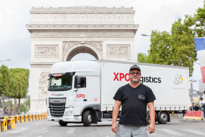 Un conductor de XPO posa delante de su camión y el Arco del Triunfo de París.