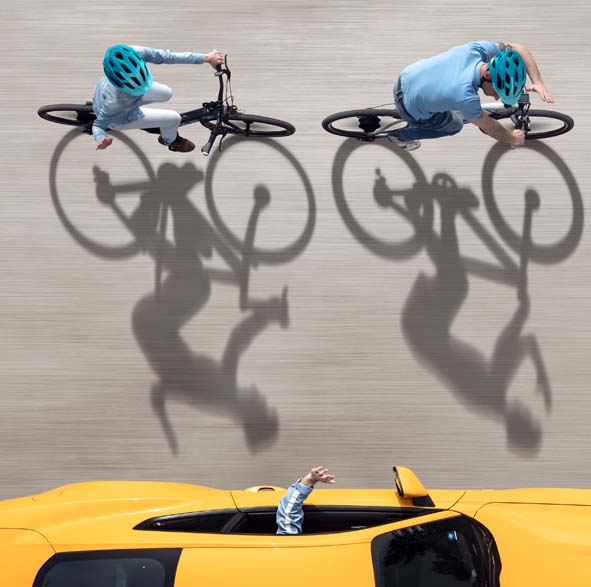 Dos ciclistas circulan junto a un coche.