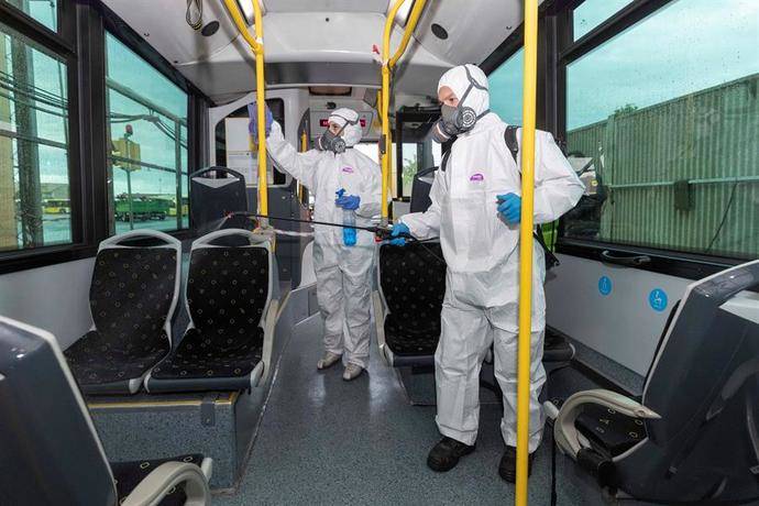 Dos trabajadores desinfectan un autobús.