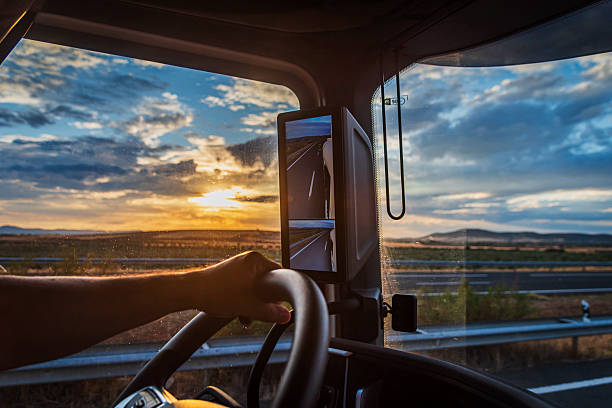 Conductor de camión manejando mientras observa el atardecer en la carretera