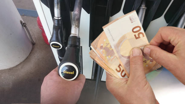 Persona usando una manguera de diesel mientras sostiene billetes de 50 euros