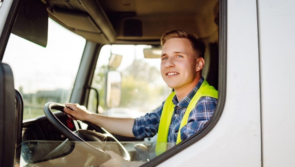 Hombre sonriente conduciendo un camión con chaleco reflectante