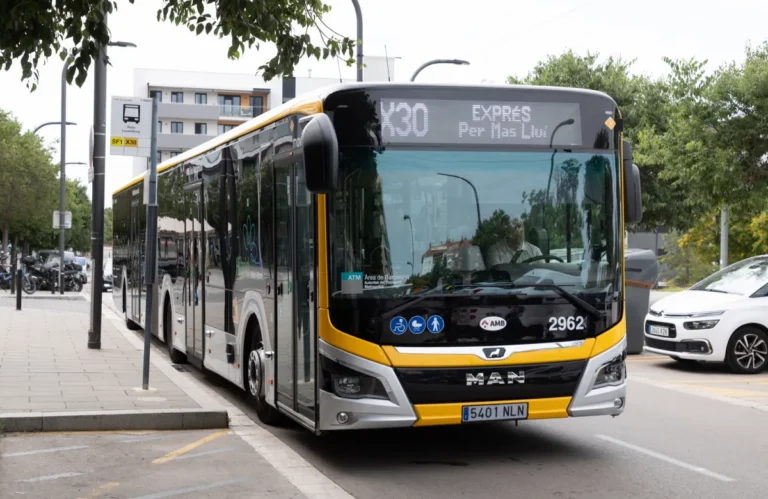 Autobús urbano blanco y amarillo de la línea X30 circula por una calle arbolada