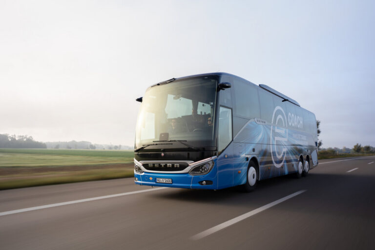 Autocar azul Setra con distintivo eCoach circula por una carretera rural.