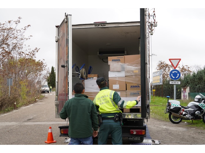 Dos personas junto a un camión abierto con cajas apiladas en su interior.