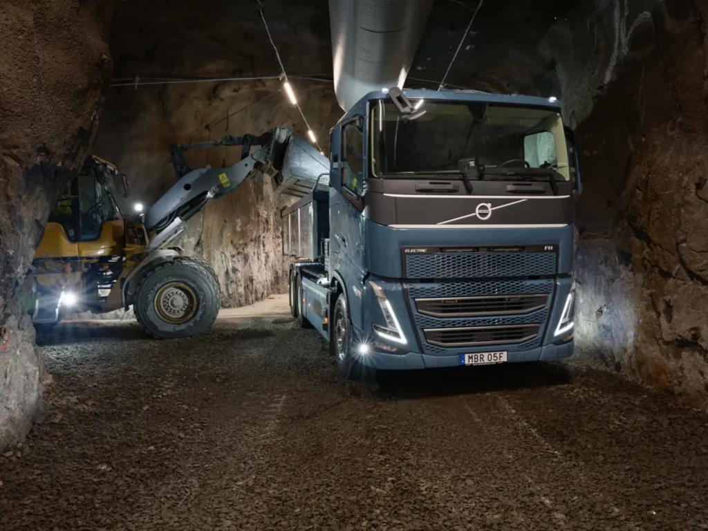 Camión Volvo y maquinaria amarilla en una galería subterránea de roca.
