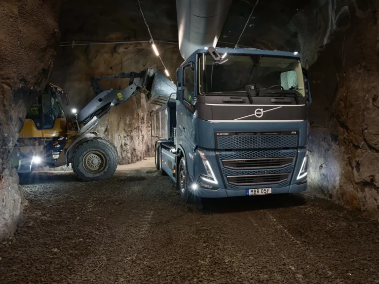 Camión Volvo y maquinaria amarilla en una galería subterránea de roca.