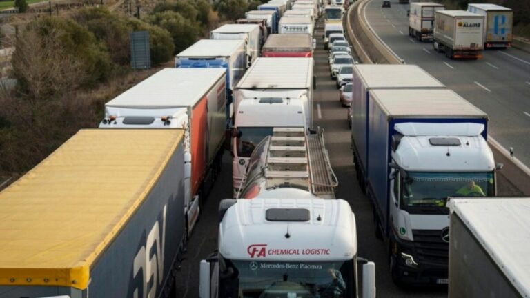 Camiones de transporte circulan muy juntos en una carretera con tráfico congestionado.