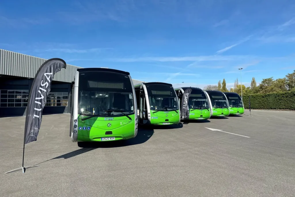 Cinco autobuses verdes de Tuvisa estacionados en fila frente a un edificio.