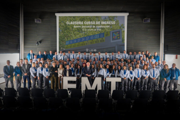 Grupo de participantes posa ante el cartel de clausura del curso de conducción de EMT Madrid.