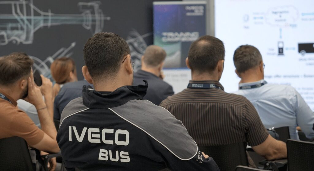 Participantes asisten a una sesión formativa de Iveco Bus frente a una pantalla.