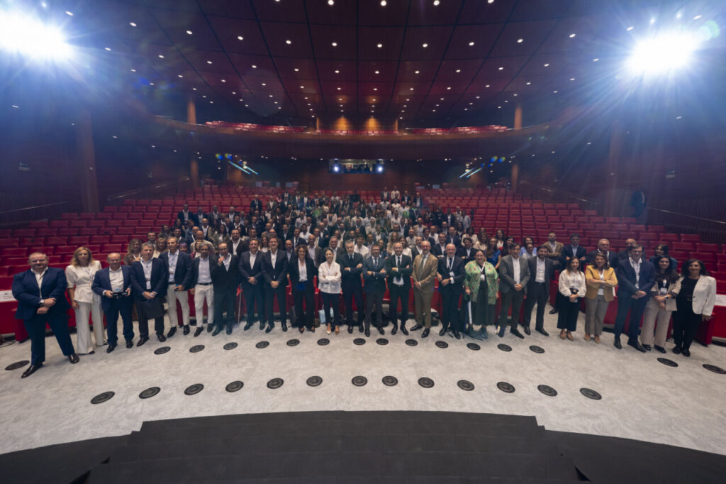 Grupo numeroso posa frente a las butacas rojas de un auditorio iluminado.