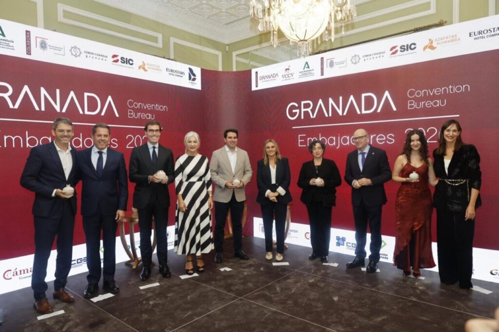 Diez personas posan ante un panel del Granada Convention Bureau durante un acto.