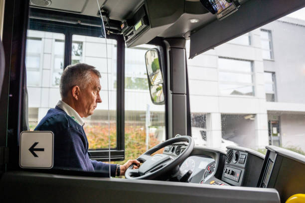 Un hombre sentado al volante dentro de la cabina de un autobús.