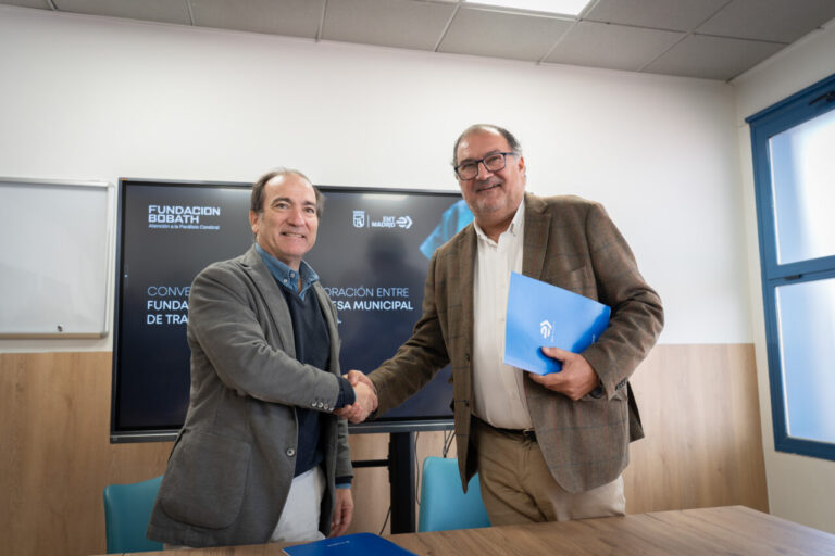 Dos hombres se estrechan la mano ante pantalla con logotipos de EMT Madrid y Fundación Bobath.