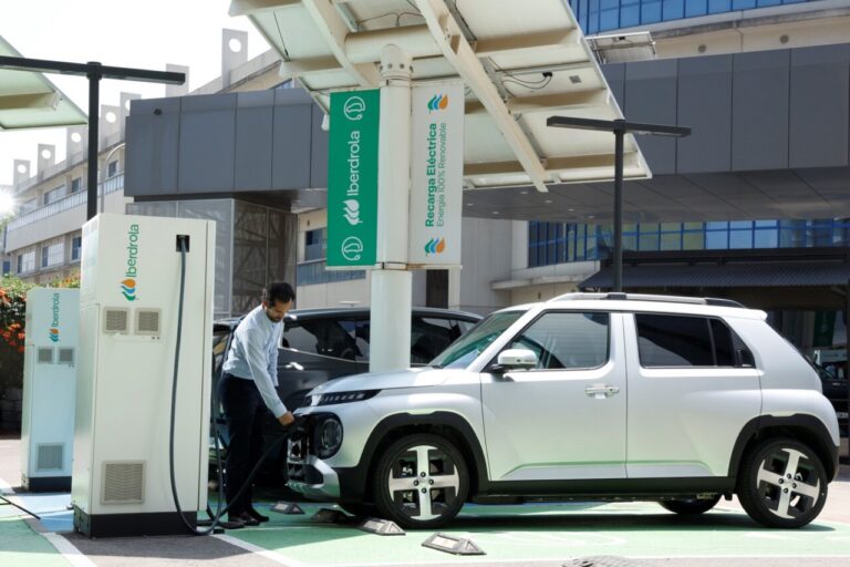 Una persona conecta un coche blanco a un punto de recarga de Iberdrola.