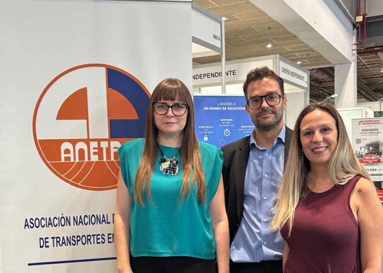 Tres personas posan frente a un expositor con el logotipo de Anetra.