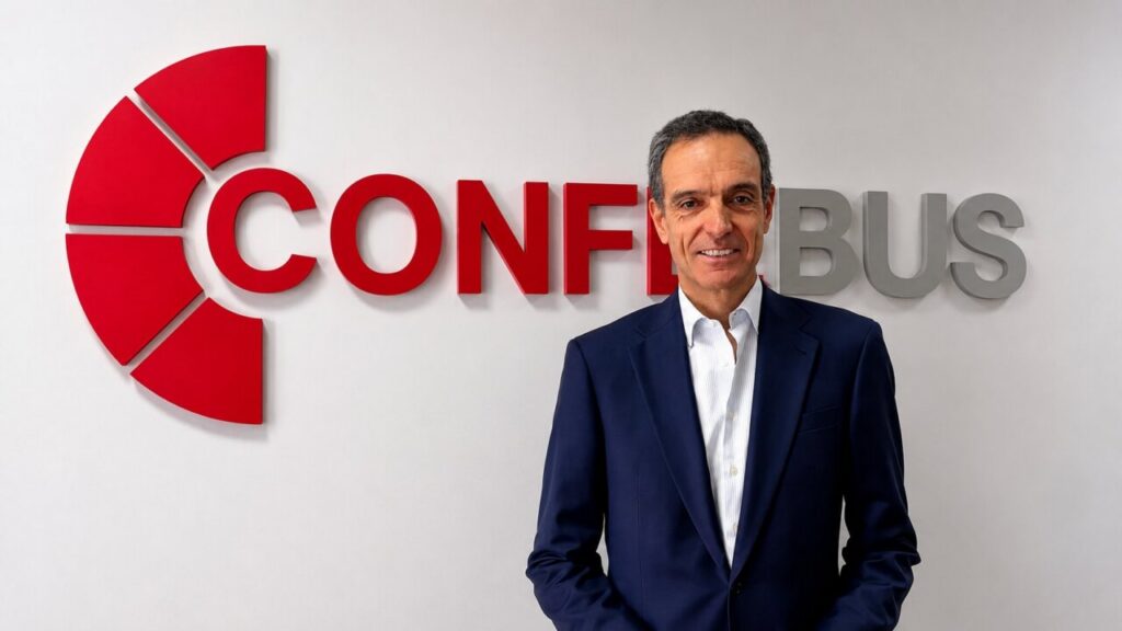 Rafael Barbadillo posa ante el logotipo de Confebús en una pared blanca.