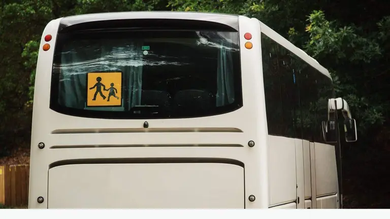 Autobús escolar con señal de advertencia en la parte trasera.